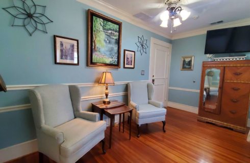 two armchairs near armoire with side table in blue room