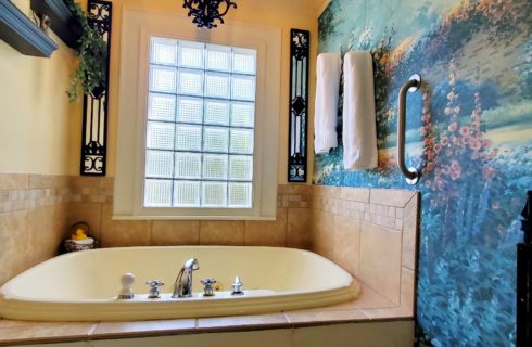 Two person whirlpool tub with garden mural wall and wrought iron fence