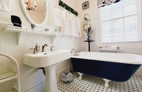 Claw foot tub and sink in white bathroom with window.