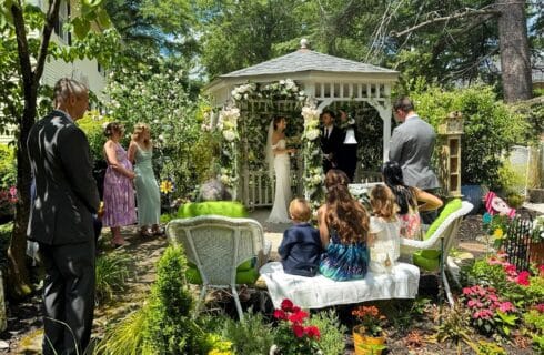 Family watching couple get married in garden gazebo ceremony.